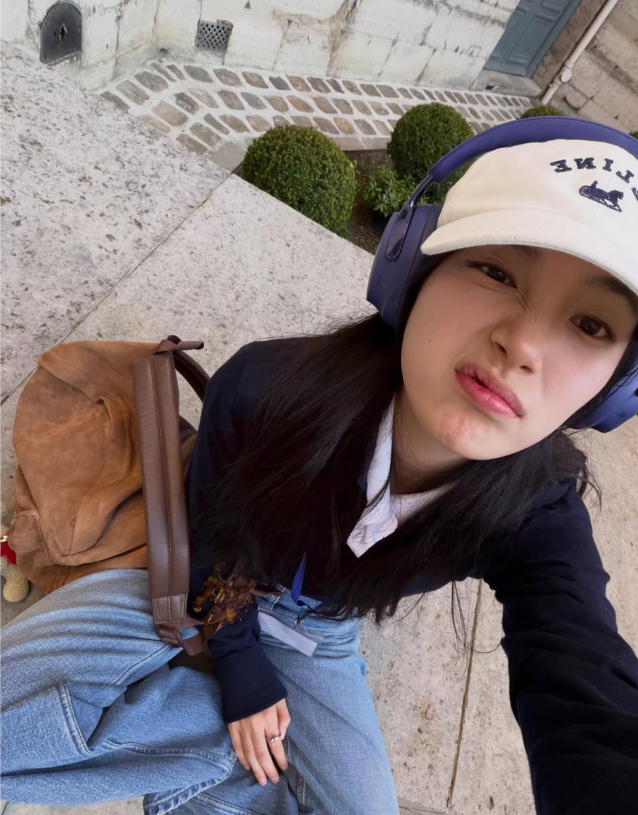 Actress Bae Suzy makes a playful face, sporting a white Celine cap and purple headphones.