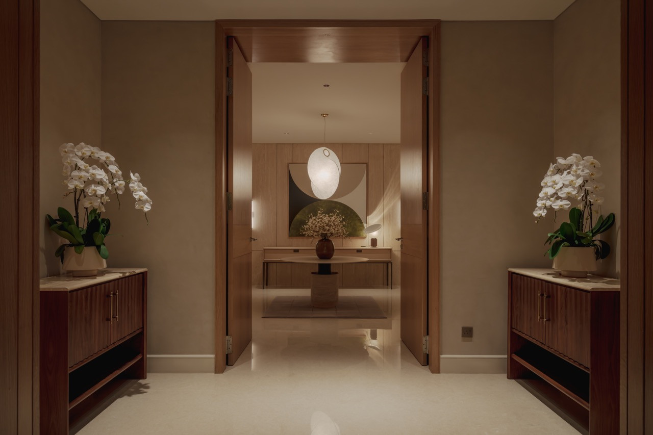 The entry gallery at Eden Taman Duta’s show unit, where travertine wall panelling and a sculptural pendant light frame the arrival sequence
