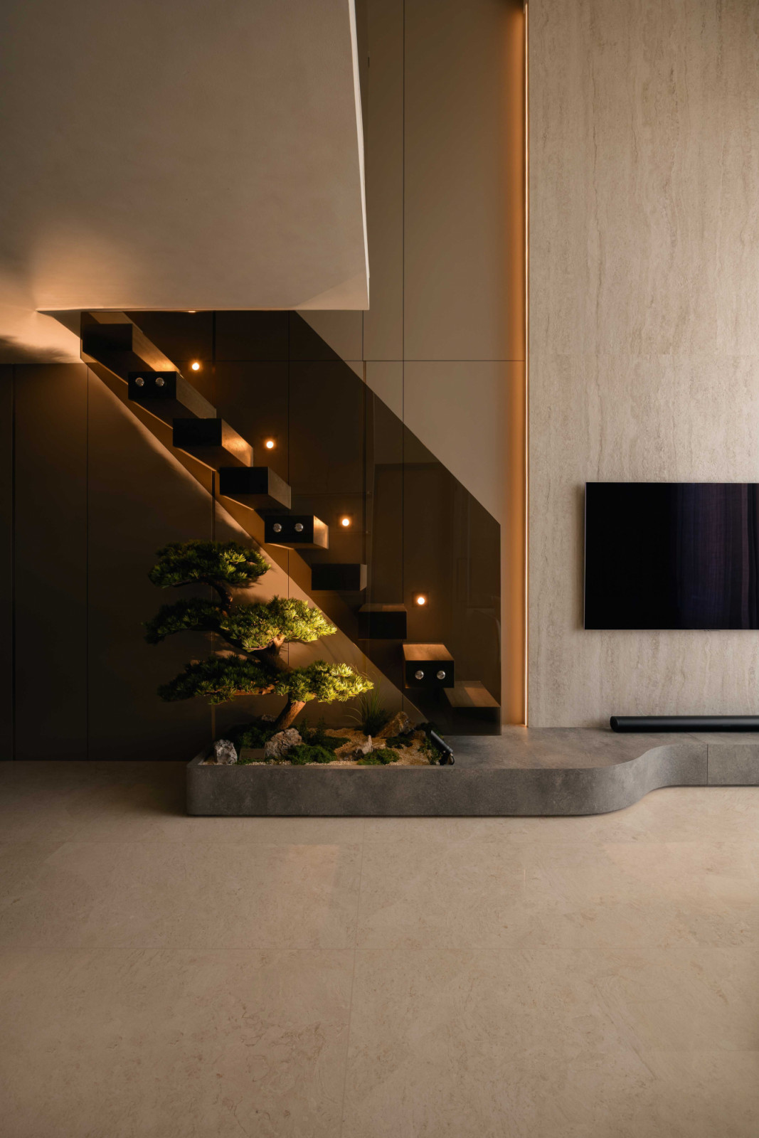 The bonsai tree tucked beneath the stairs, a biophilic touch that grounds the space