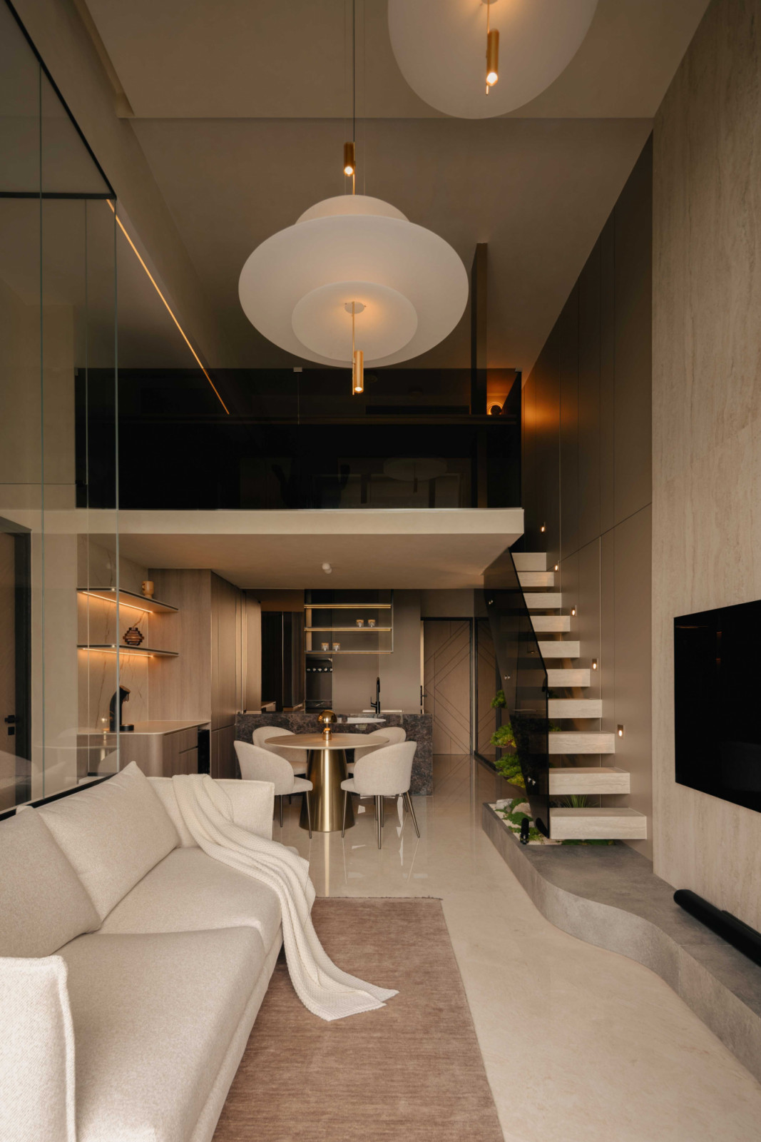 The double-volume living and dining area, anchored by the floating staircase and loft study