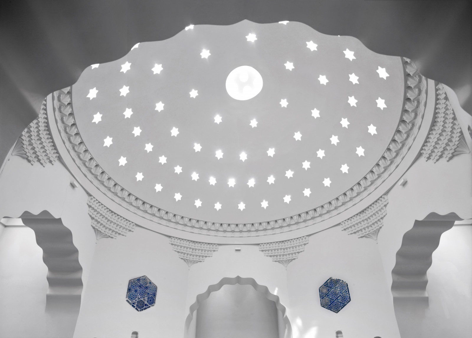 Star-shaped openings pierce the dome of the hot room at Zeyrek Çinili Hamam, scattering daylight across the marble below