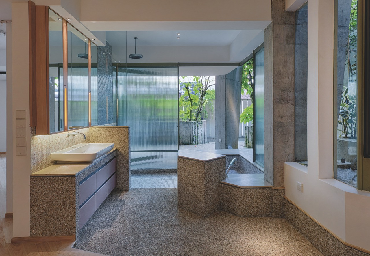 A terrazzo-topped vanity and glass-enclosed shower in one of the bathrooms, fitted with ribbed and fluted glass screens that diffuse light in the manner of traditional shoji dividers