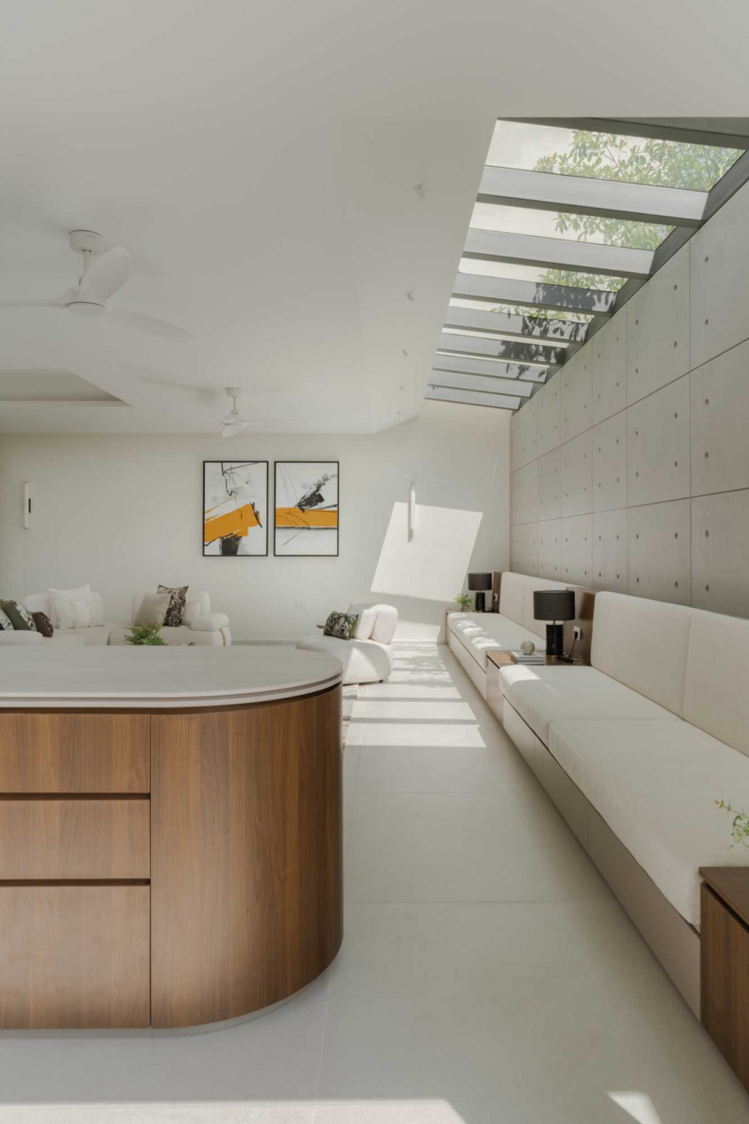 Filtered daylight plays across concrete through an aluminium-slatted skylight at the basement level