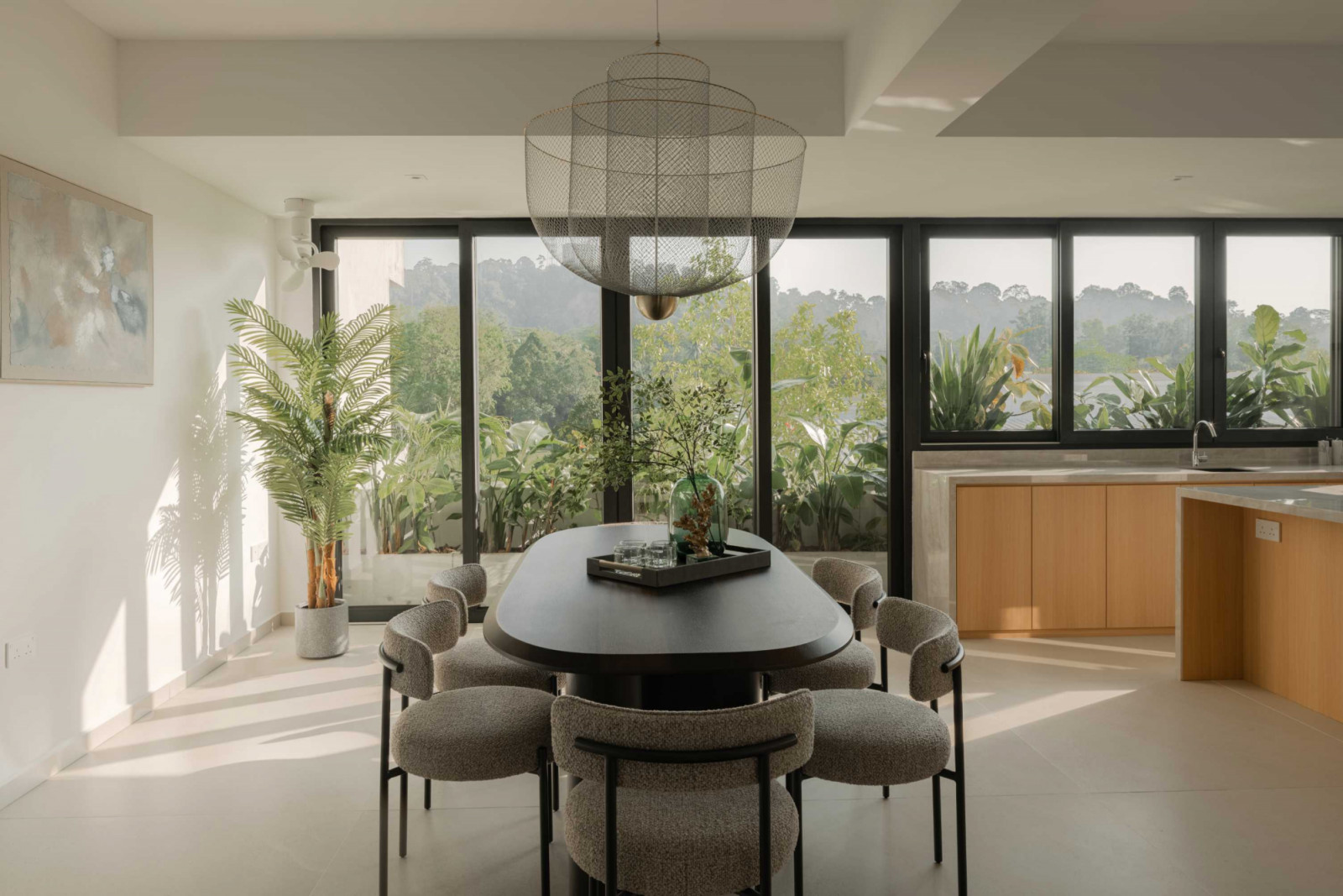 The dining area centres on an elongated table and is framed by greenery