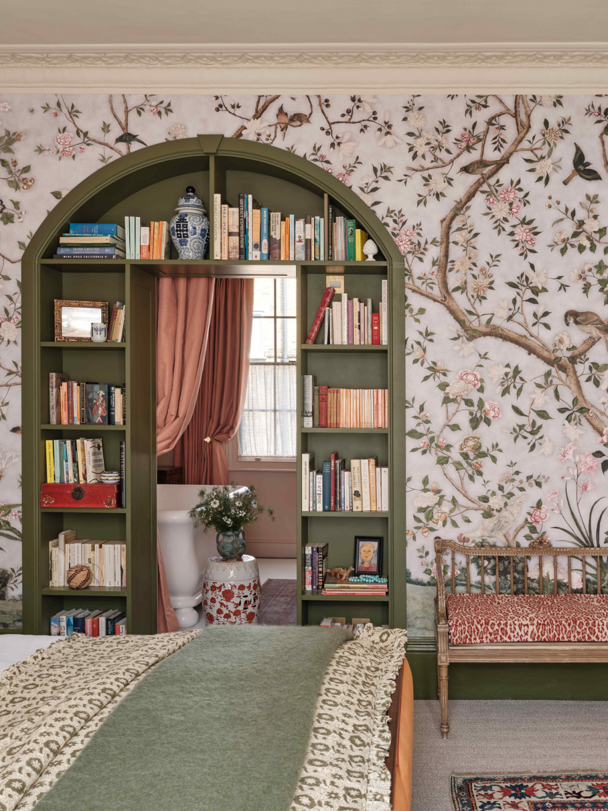 An arched bookcase frames the adjoining doorway into the en-suite bathroom