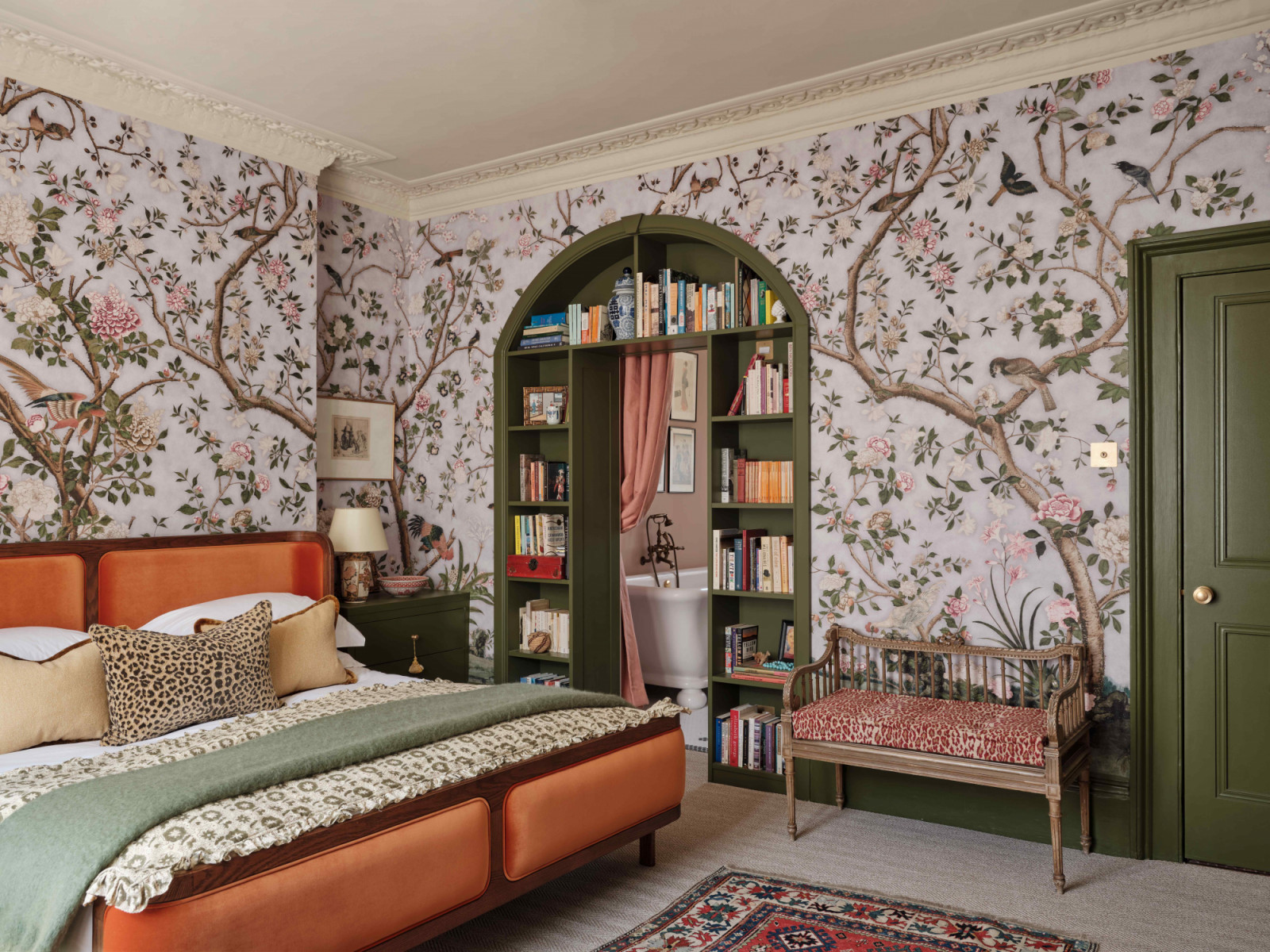 A petal-pink Chinoiserie-style wallpaper is paired with a vibrant tangerine velvet bed from Soho Home