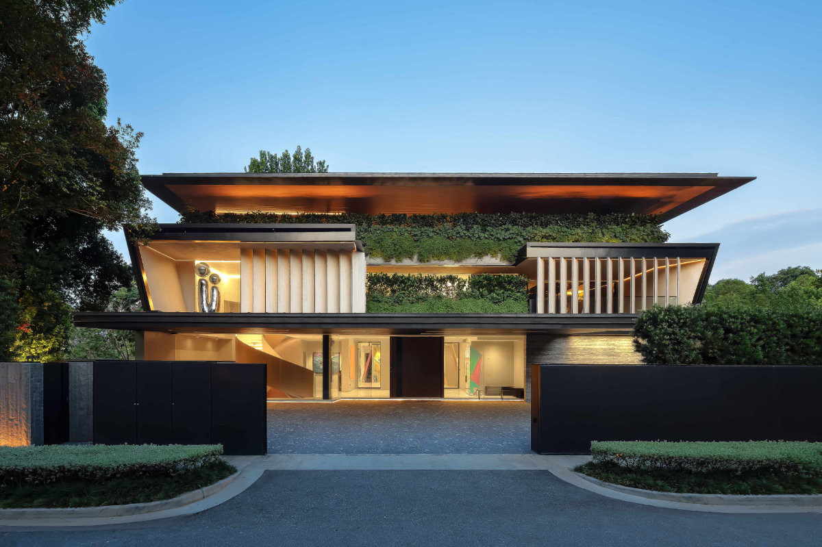 The house glows in the evening, its generous overhang creating a shaded forecourt and carport canopy