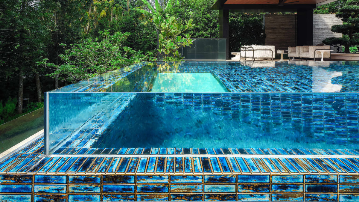 A structural glass edge reveals the infinity pool’s Japanese artisanal glazed tiles, which shift from sapphire to turquoise with the light