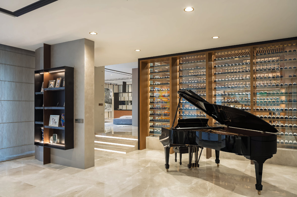 The wine cellar make a dramatic backdrop to the Steinway piano in the living area