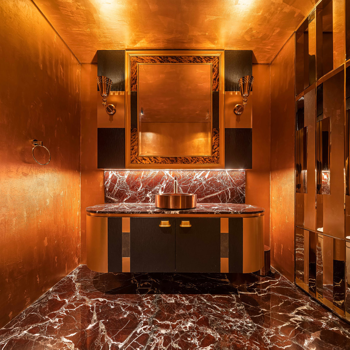 This powder room complements Rosso Levanto marble with warm metallic finishes for a more dramatic, intimate character