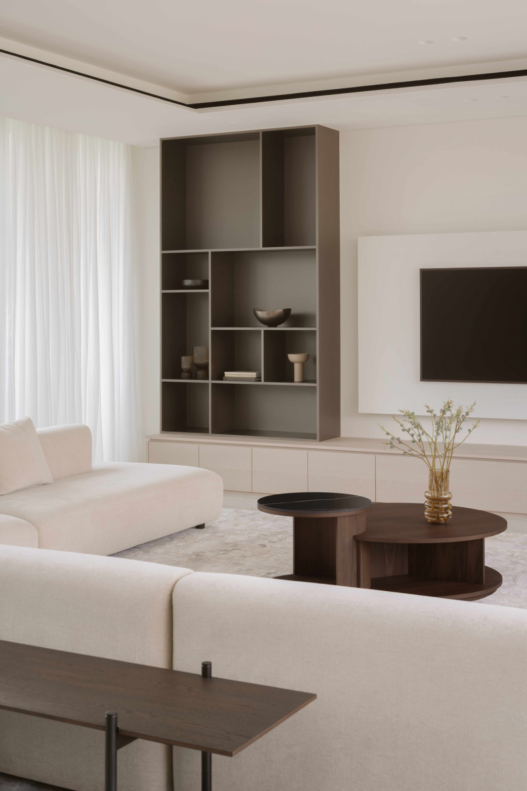 Grey display carpentry stands out against the understated colour palette of the bungalow’s living room