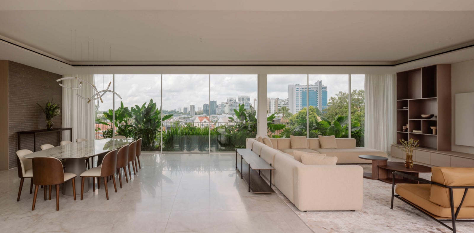 The bungalow’s dining and living areas share a continuous span of floor-to-ceiling glass, drawing the neighbourhood’s greenery and distant cityscape into the room