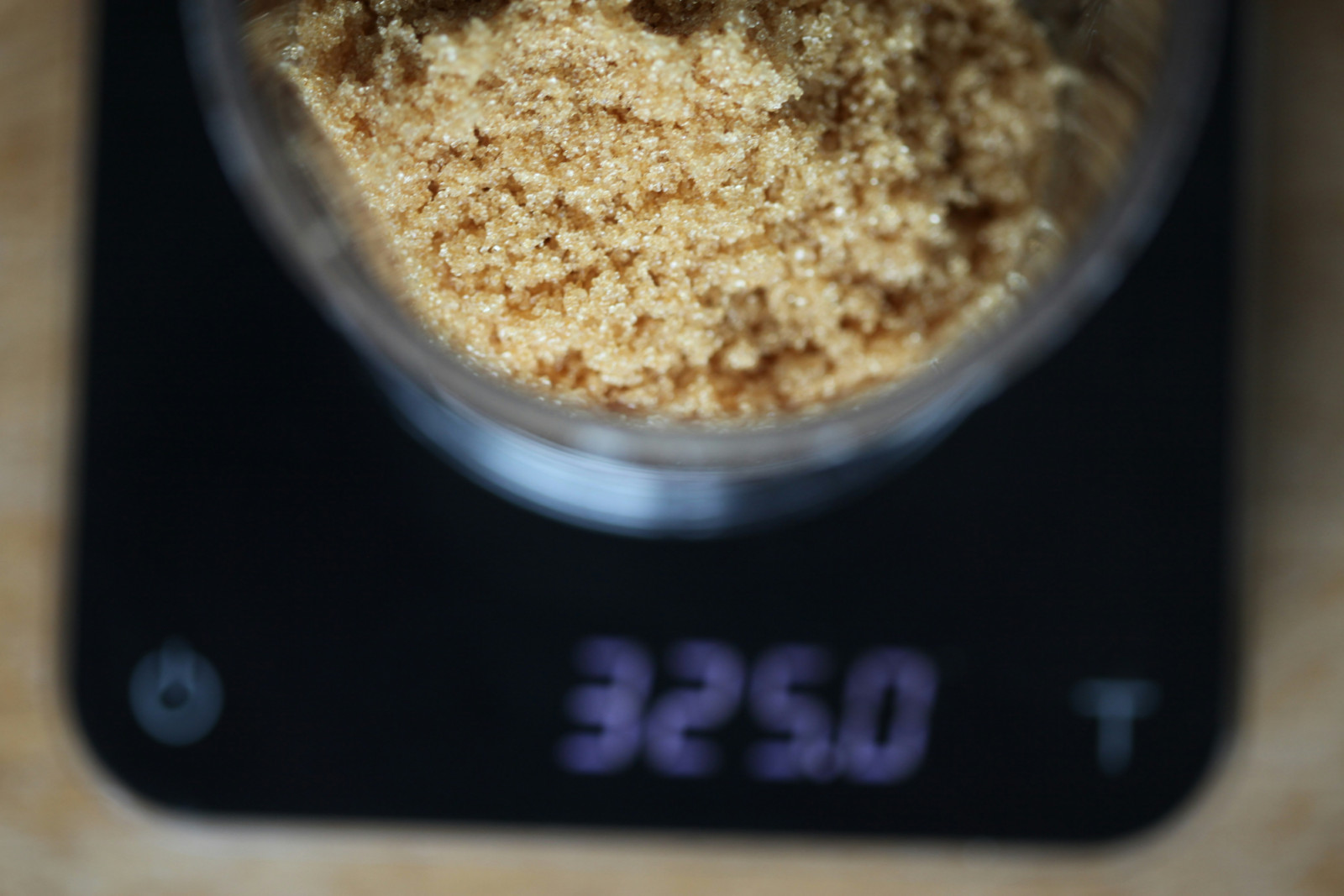 Brown sugar is weighed on a digital scale, displaying 325.0 grams.