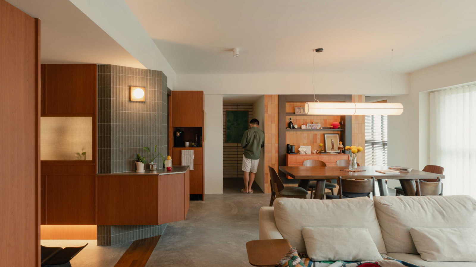 Exposed screed flooring and timber cabinetry frame the open flow between the living and dining areas