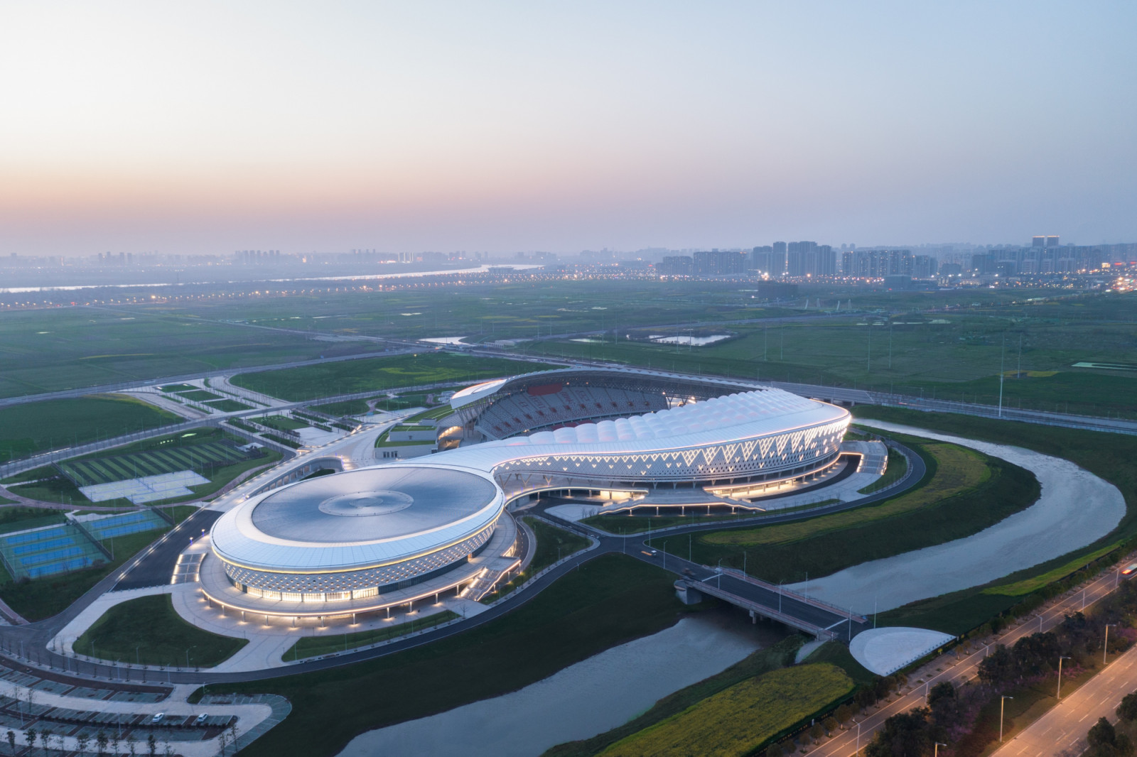 At dusk the canopy is lit from within, tracing a continuous line from the stadium bowl to the neighbouring circular building in the 138,000-square-metre sports complex. (Photo: Yilong Zhao)
