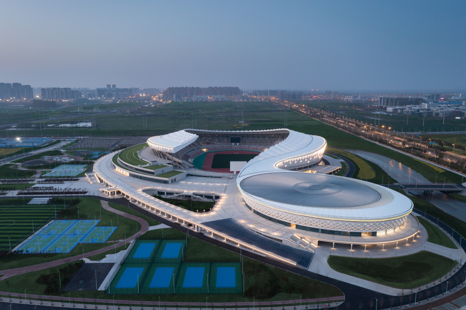 The 30,000-seat stadium has a canopy that sweeps over the stands but leaves one side of the bowl open, with outdoor courts and pitches for public use beyond (Photo: Yilong Zhao)