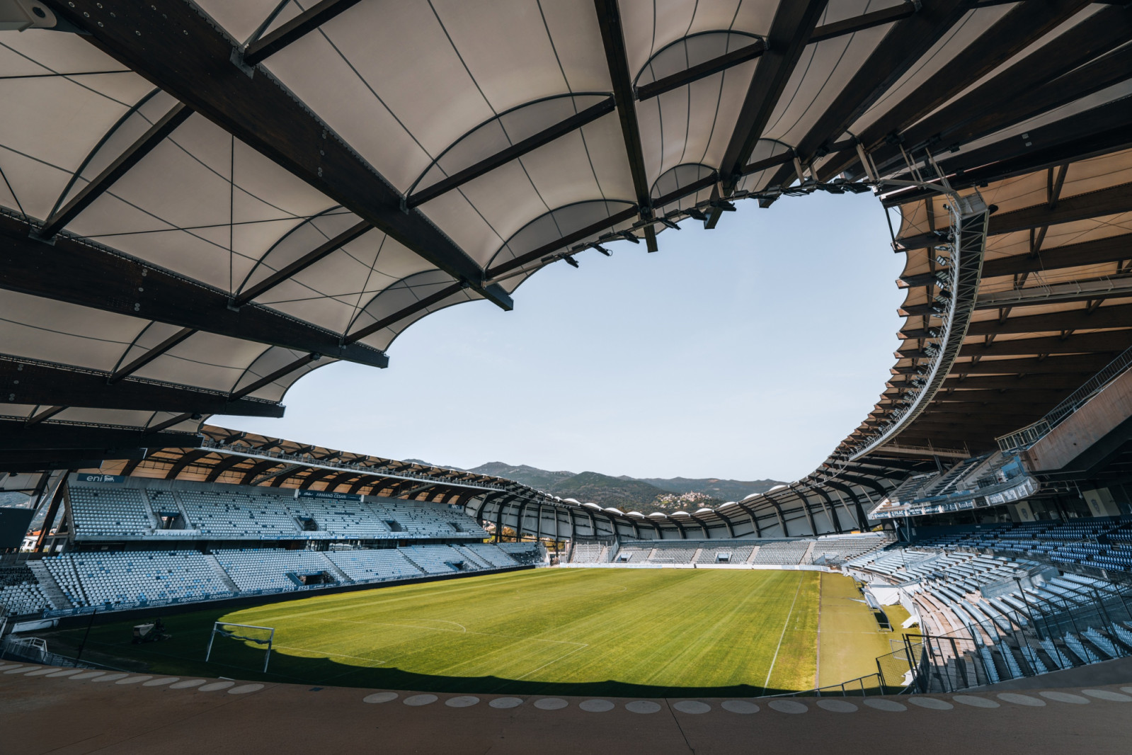 Membrane panels stretched over a timber framework form the canopy, which leaves an open oval above the pitch, looking towards the mountains (Photo: Banzaiprod)