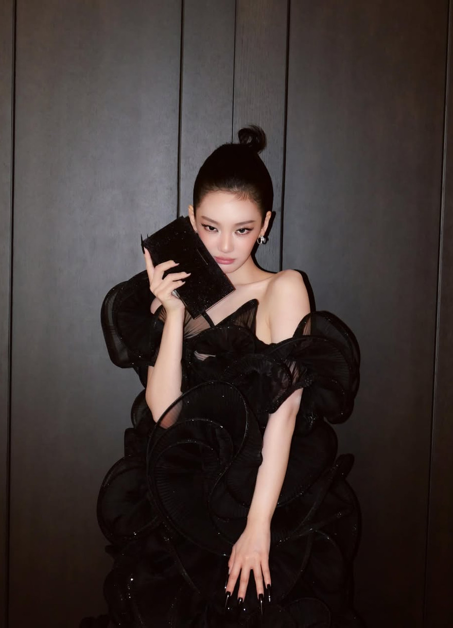 Ningning, K-pop idol, embodies her signature style in a stunning black ruffled gown, complete with a sleek updo and statement nails.