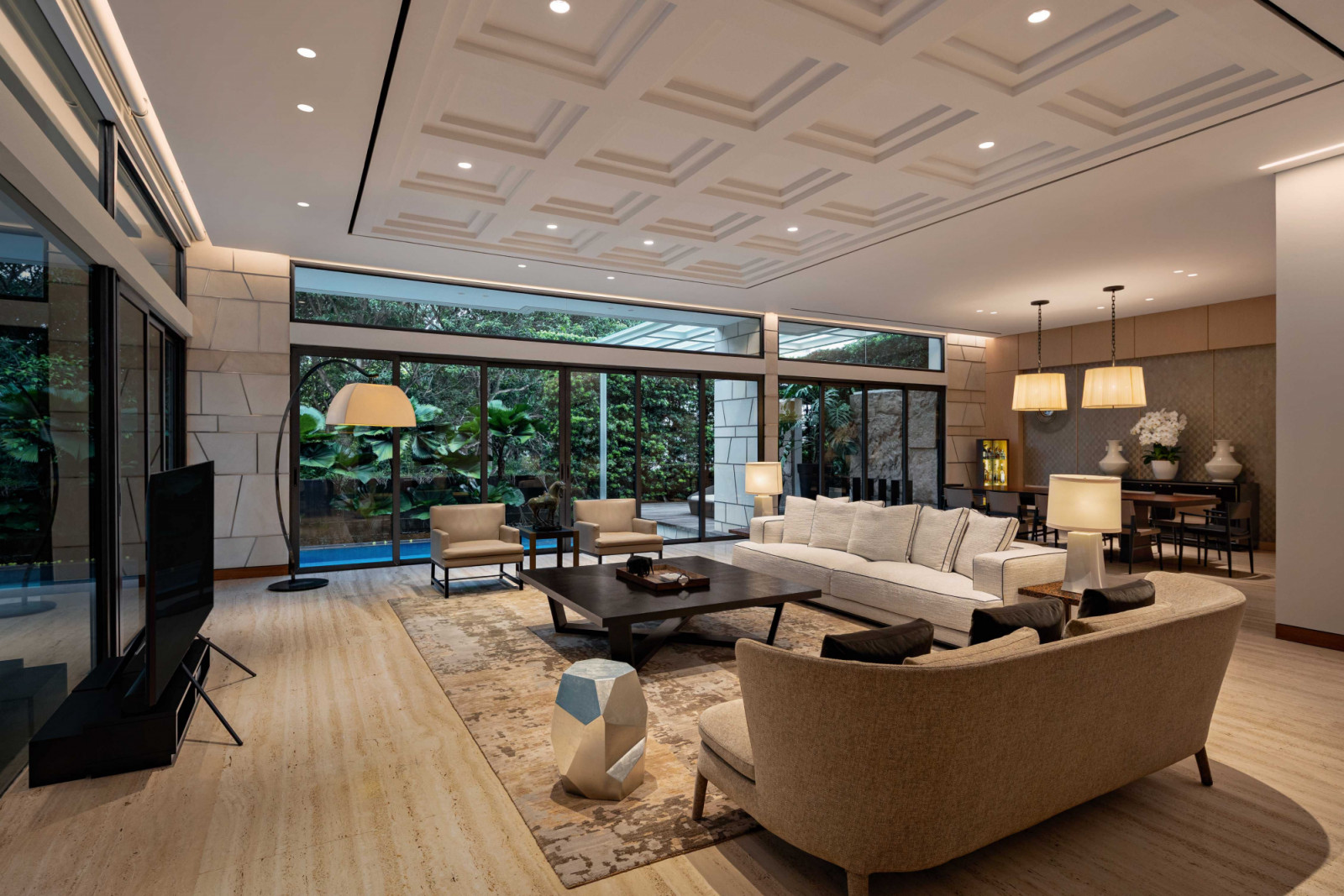 The well-appointed living and dining areas look out to lush greenery and an inviting lap pool