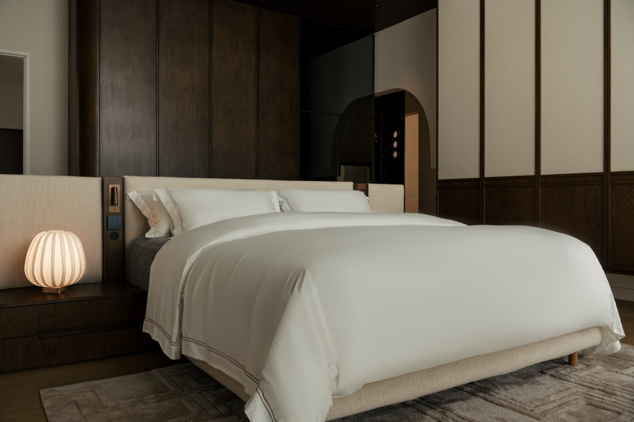 The master bedroom, finished in dark walnut and soft neutrals; a view through the master suite