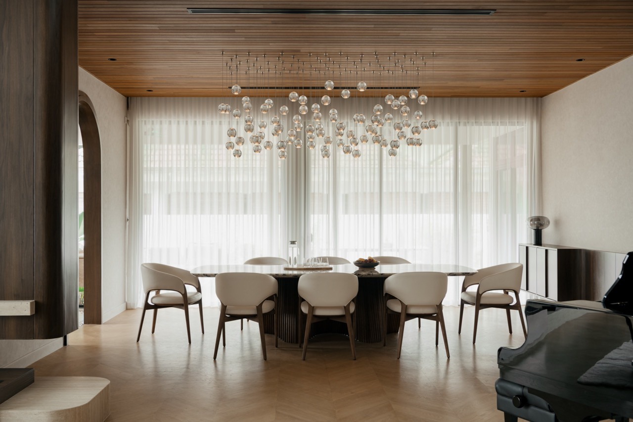 The dining table and chairs are by Minarch, set beneath a cascade of glass pendants and a timber-slatted ceiling