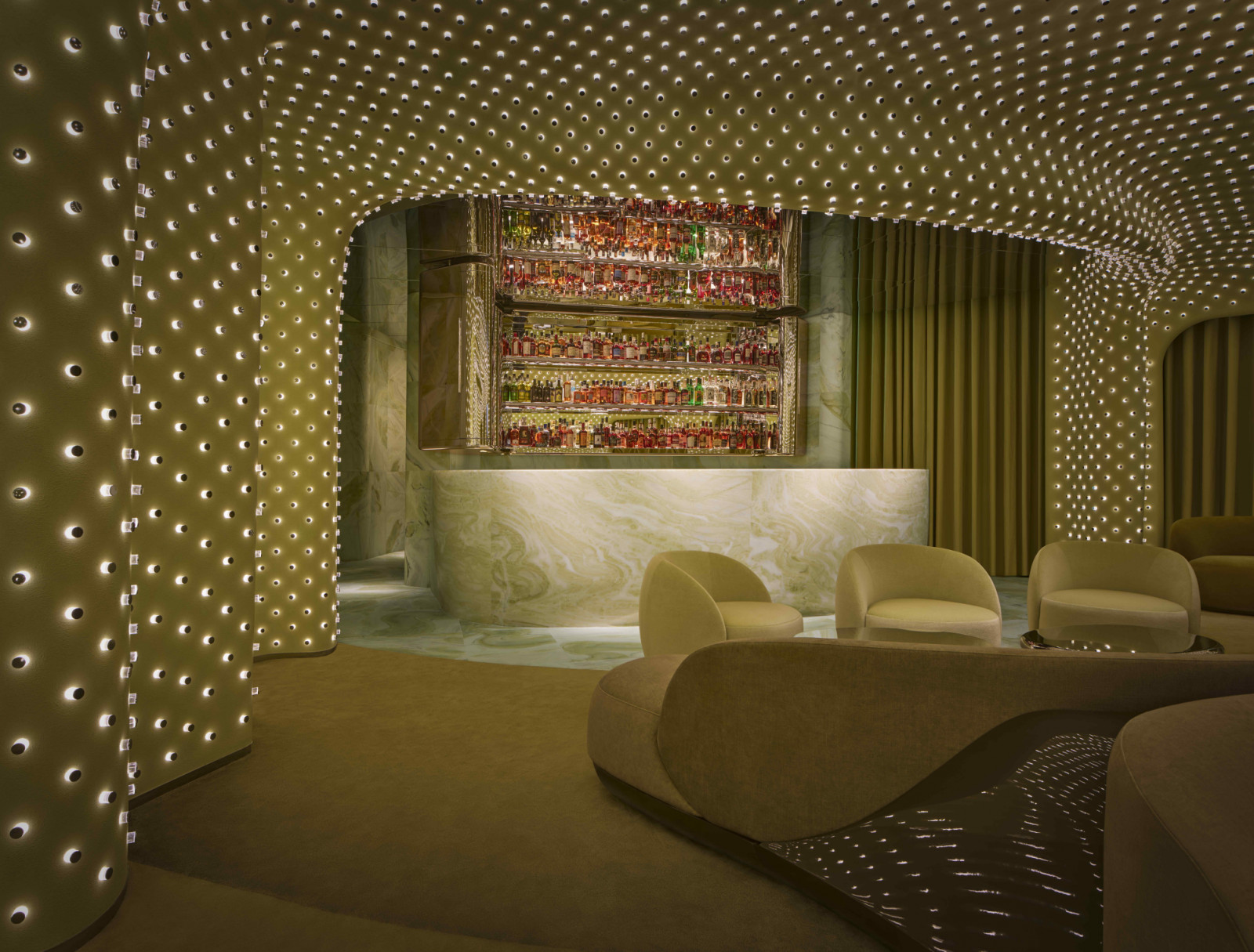 The sculptural green marble bar provides a striking counterpoint to the ethereal interior