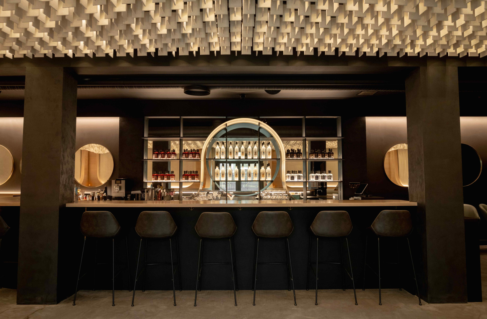 Brass accents and column stills establish a tactile, industrial character