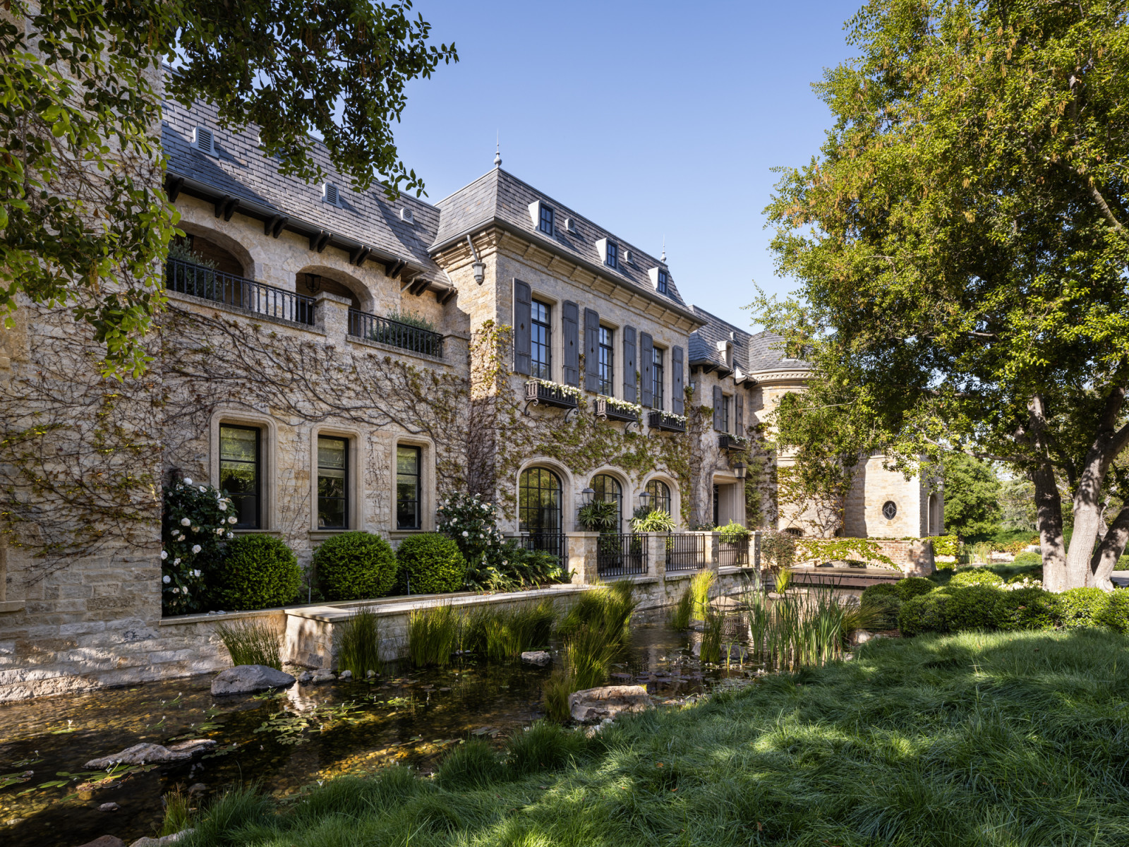 The residence of French château grandeur appears to float above a signature water feature