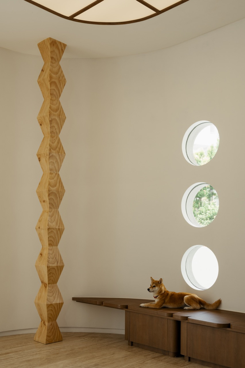 Three porthole windows along a corridor styled with a sculptural timber totem and a resin dog figurine