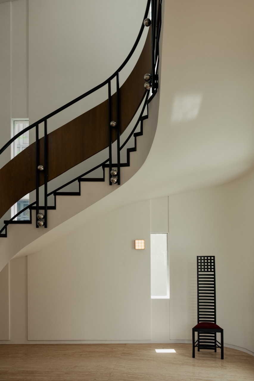 The curved staircase that sweeps through the centre of the house, framed in dark wood and black metal