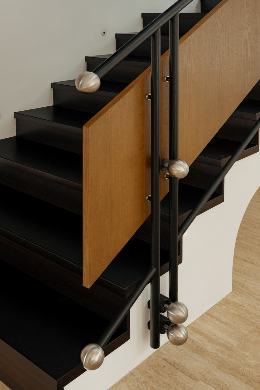 A closer view of the staircase, its black treads and timber panel