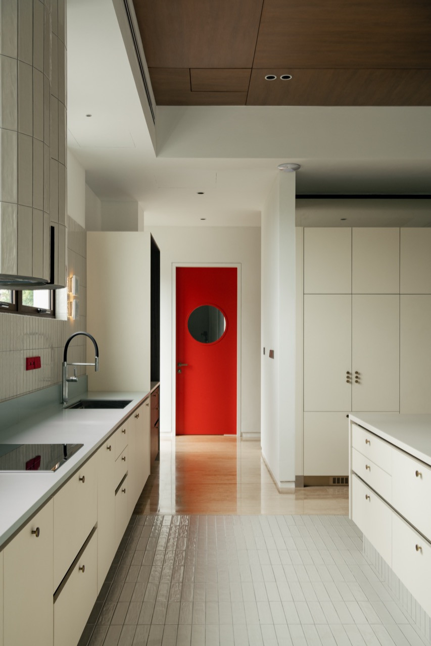 A corridor leading to the wet kitchen, its red-painted door standing out against the neutral palette