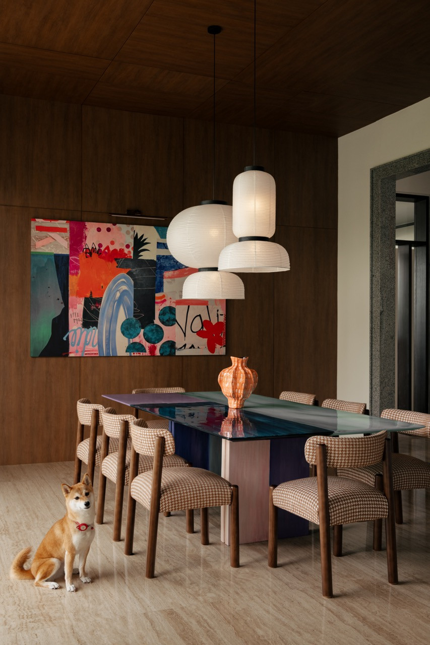 The family's dog beside the dining table, set beneath a cluster of paper pendant lights and a large abstract canvas